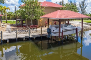 A waterfront property with a dock, a covered boat storage area, and a house with a red roof. - Pirate's Cove (Punta Gorda)