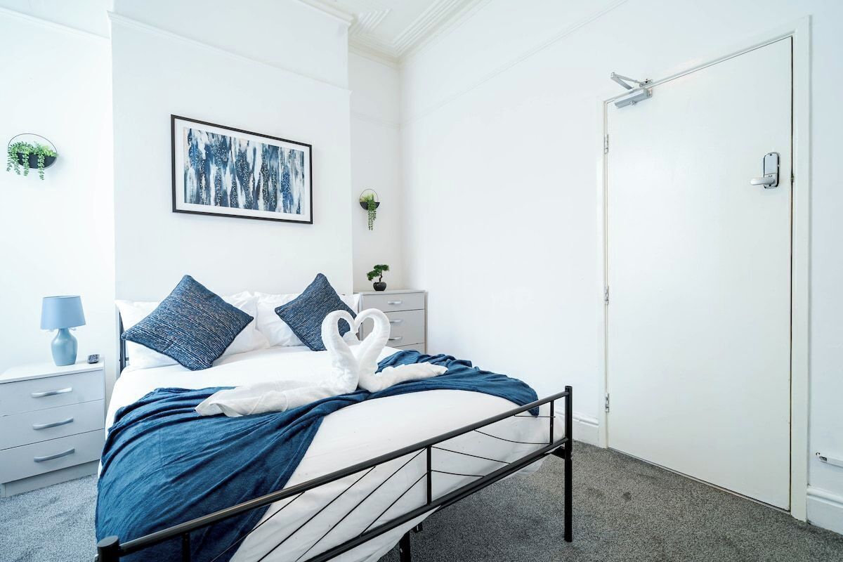 Ein Hotelzimmer mit einem Bett, einem Nachttisch, einem Wandbild und einer Tür.