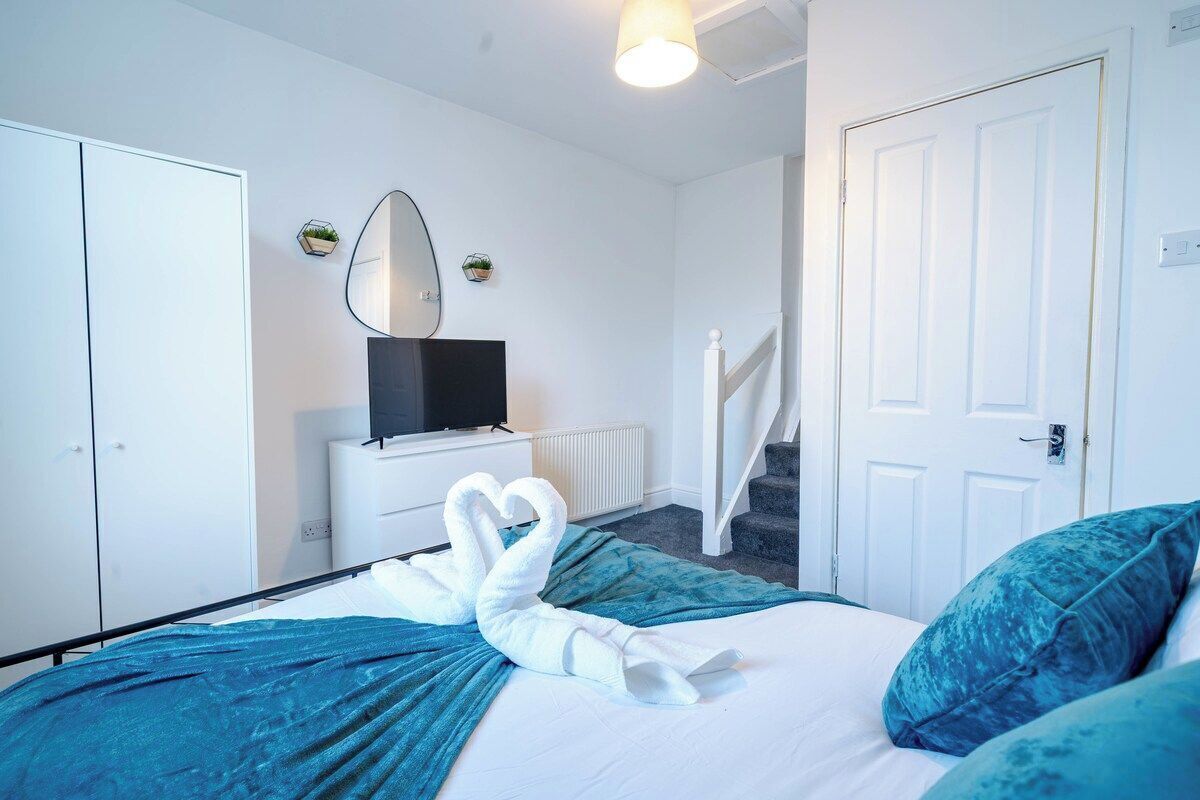 A hotel room with a bed, a TV, a white door, and a staircase.