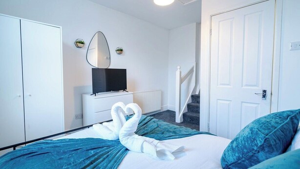 Ett hotellrum med en säng, en tv, en vit dörr och en trappa.