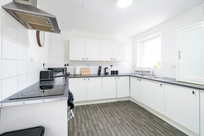 A modern kitchen with white cabinets, a black countertop, and a built-in stove. - Birkenhead CH43 | Spacious 6BR Home | Sleeps 12 (Birkenhead)
