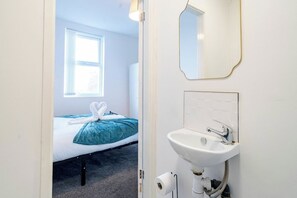 Una camera con un letto, una finestra, un lavandino e uno specchio.