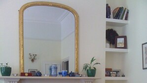 Ein Wohnzimmer mit Kamin, einem großen Spiegel, einer Bücherwand und einem Sofa.