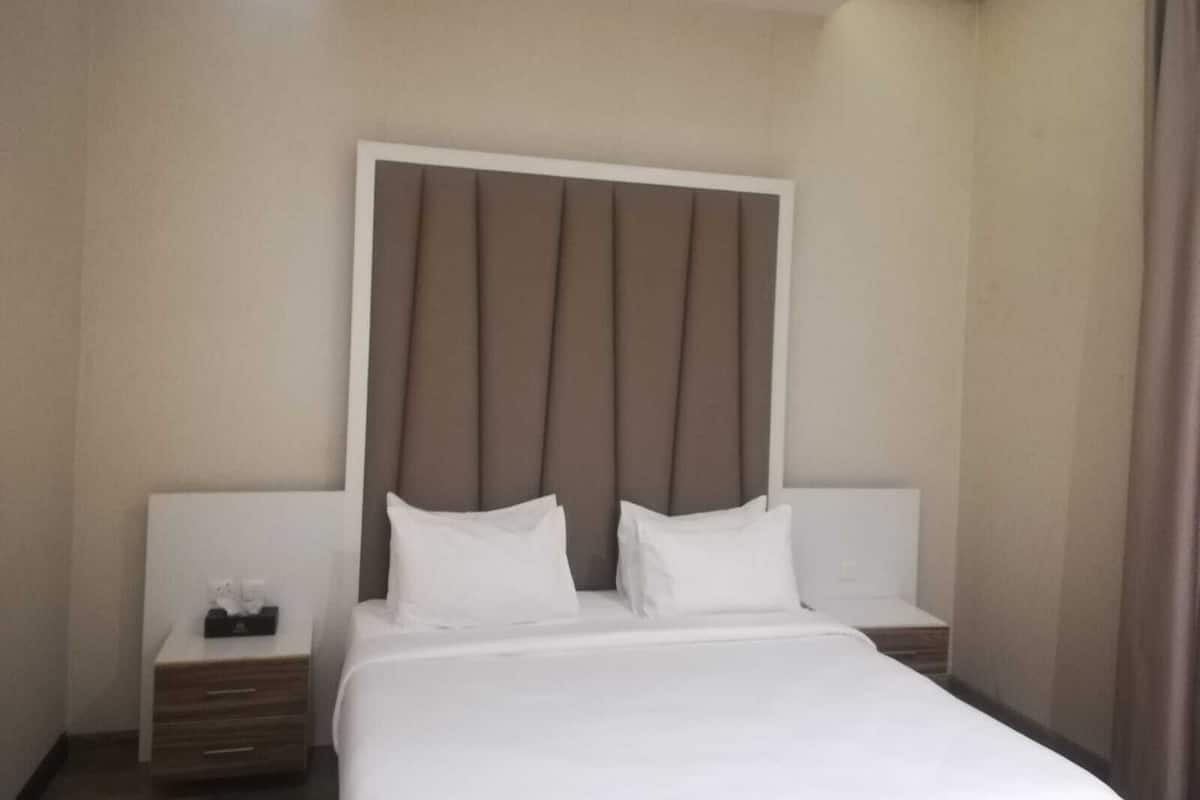A hotel room with a large bed, two bedside tables, and a headboard.