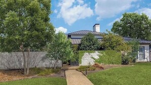 Ein Wohnhaus mit befestigter Auffahrt, Rasen und einer Steinmauer.