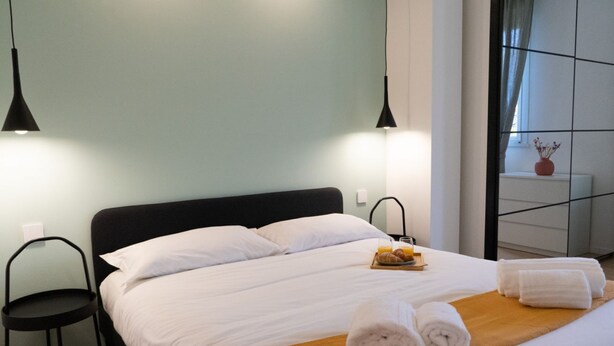 A neatly made bed with white linens, a wooden headboard, and a breakfast tray with croissants and juice. - Newly renovated apartment, located in the lively Bicocca area, right in front of the Arcimboldi Theatre, which offers shows and concerts throughout the year.The location is ideal: a stone's throw from the Greco train stop, from which you can reach the  (Milano)