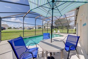 Eine überdachte Terrasse mit Pool, blauen Stühlen und einem Tisch.