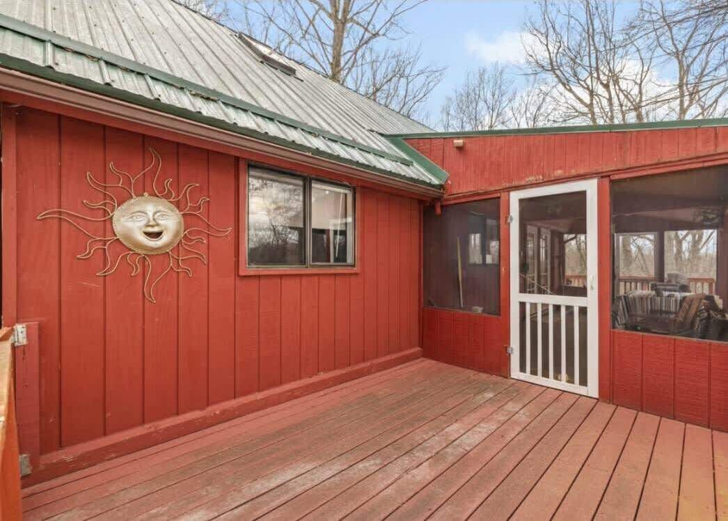 Un bâtiment en bois rouge, doté d’un toit en métal, d’un porche couvert et d’un motif décoratif en forme de soleil sur le mur.