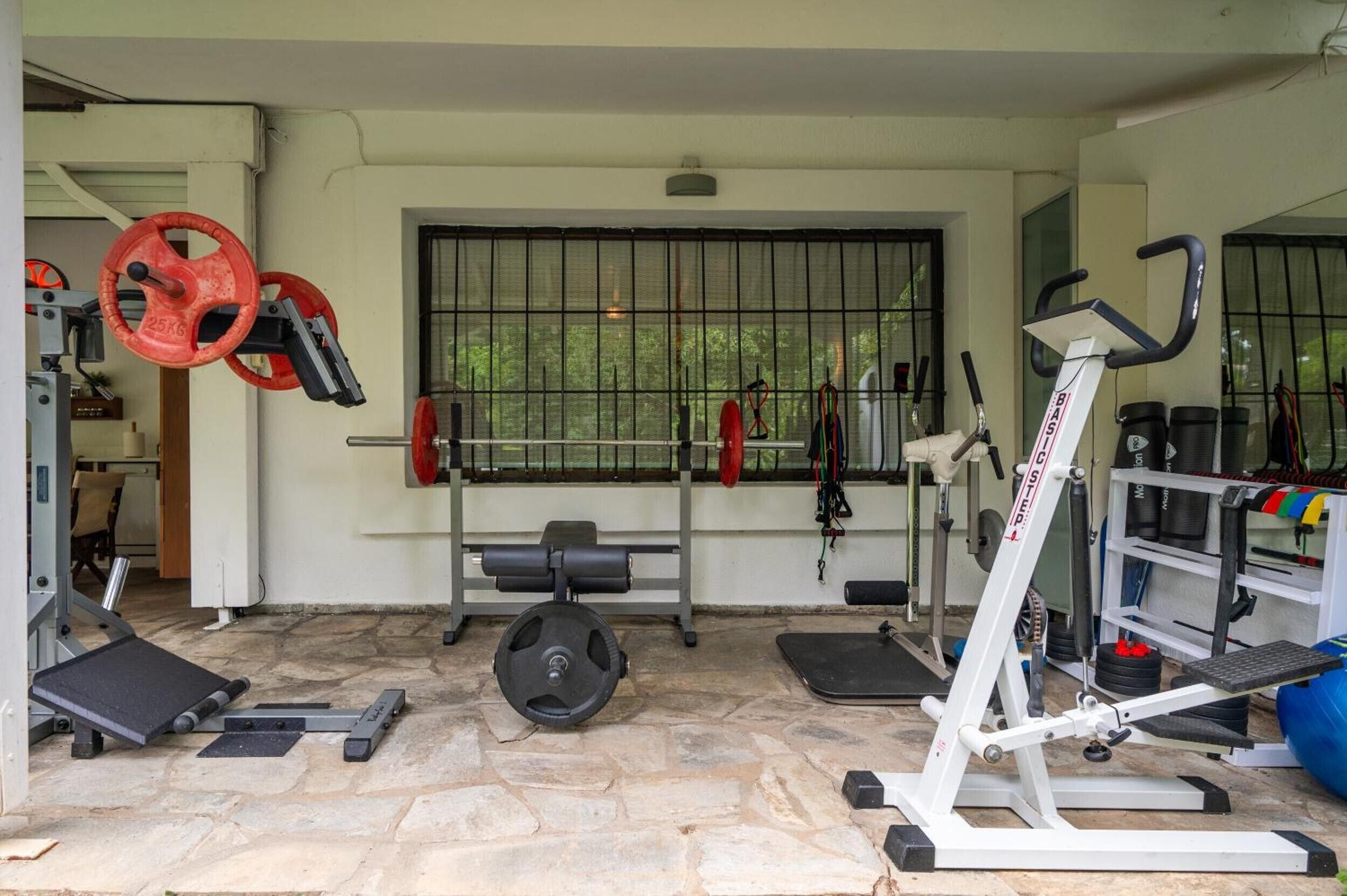 A gym with weightlifting equipment, a bench, and a treadmill.