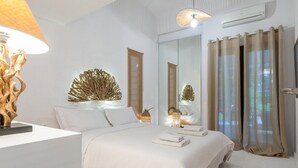 A modern bedroom with a large bed, a mirror, a wall-mounted light fixture, and a window with curtains.
