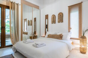 Quarto com uma cama grande, um espelho e vista para o exterior.