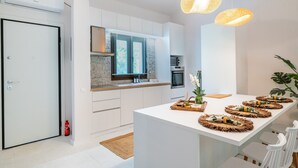 A modern kitchen with white cabinetry, a built-in stove, and a large island with decorative mats.