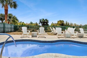A swimming pool with white lounge chairs and a green fence. - Southern Charm (Port St. Joe)