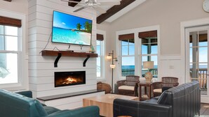 A modern living room with a fireplace, comfortable seating, a television, and a view of the ocean. - Southern Charm (Port St. Joe)