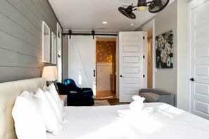 A modern hotel room with a large bed, a desk, a chair, and a door leading to a bathroom. - Southern Charm (Port St. Joe)