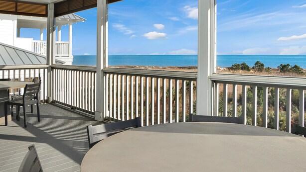 A covered outdoor area with a table and chairs, overlooking a beach. - Southern Charm (Port St. Joe)