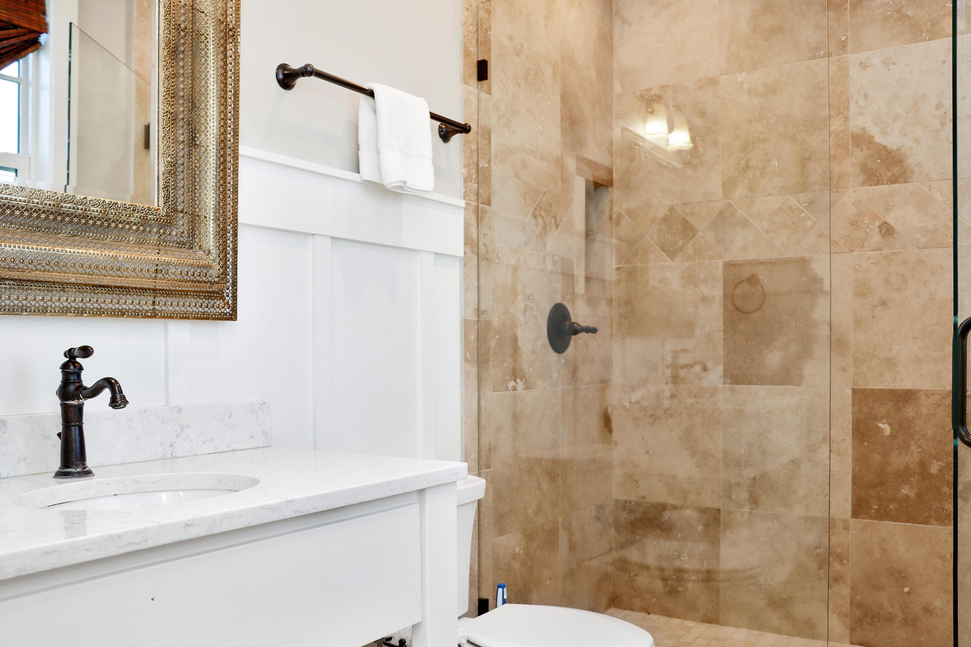 A bathroom with a white sink, a mirror with an ornate frame, and beige tiled walls.