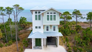 A two-story house with a garage, surrounded by pine trees and a view of the ocean. - West Wind (Port St. Joe)