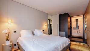 Un dormitorio moderno con una cama grande, lámparas de noche y una pequeña planta en maceta.