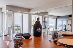 A dining table set with various glassware and a bottle labeled "LSO PASSION" in a modern kitchen with large windows. - L'Écrin des Sables 4*, an exceptional 70 m2 seafront location (Les Sables-d'Olonne)