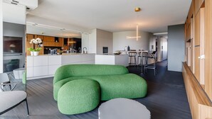 Una cocina moderna con armarios blancos, una isla central y un comedor con taburetes de bar.