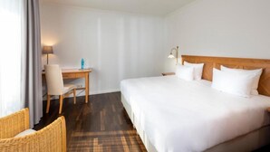 A hotel room with a bed, a desk, a chair, a ceiling fan, and a lamp. - Sunday Resort Rugen Double Room Disability Access (Sagard)