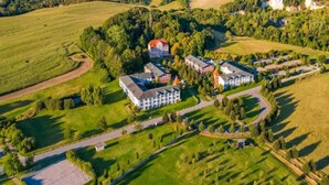 An aerial view of a resort with multiple buildings, green fields, and a body of water in the background. - Sunday Resort Rugen Double Room Disability Access (Sagard)