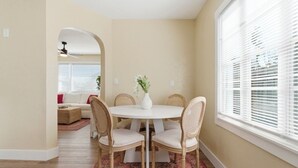 Een eetruimte met een ronde tafel, vier stoelen en een bloevas.