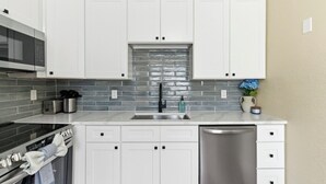 Een moderne keuken met witte kasten, een roestvrijstalen spoelbak en een betegelde achterwand.