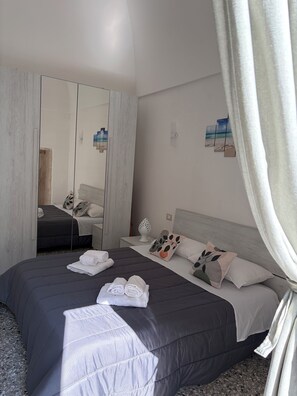 Habitació d'hotel moderna amb un llit gran, un taulell de nit i una paret decorada amb una imatge de platja.