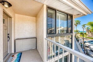 A balcony with a view of palm trees and a building. - Walk-Out Beachfront Condo | Sleeps 7 | Heated Pool | Old Florida Charm (Longboat Key)