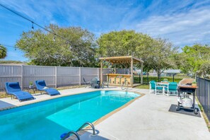 A backyard with a swimming pool, lounge chairs, a barbecue grill, and a wooden pergola. - Seaside Villa (St. Augustine)