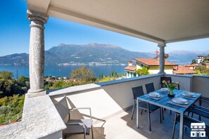 Eine Terrasse mit Esstisch, mit Blick auf einen See und Berge.