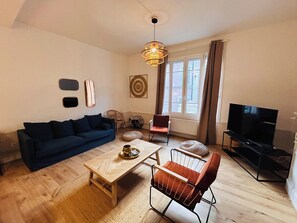 A living room with a sofa, coffee table, and a TV. - Le Millésime Barbatre | Centre-ville | 7 couchages (Reims)