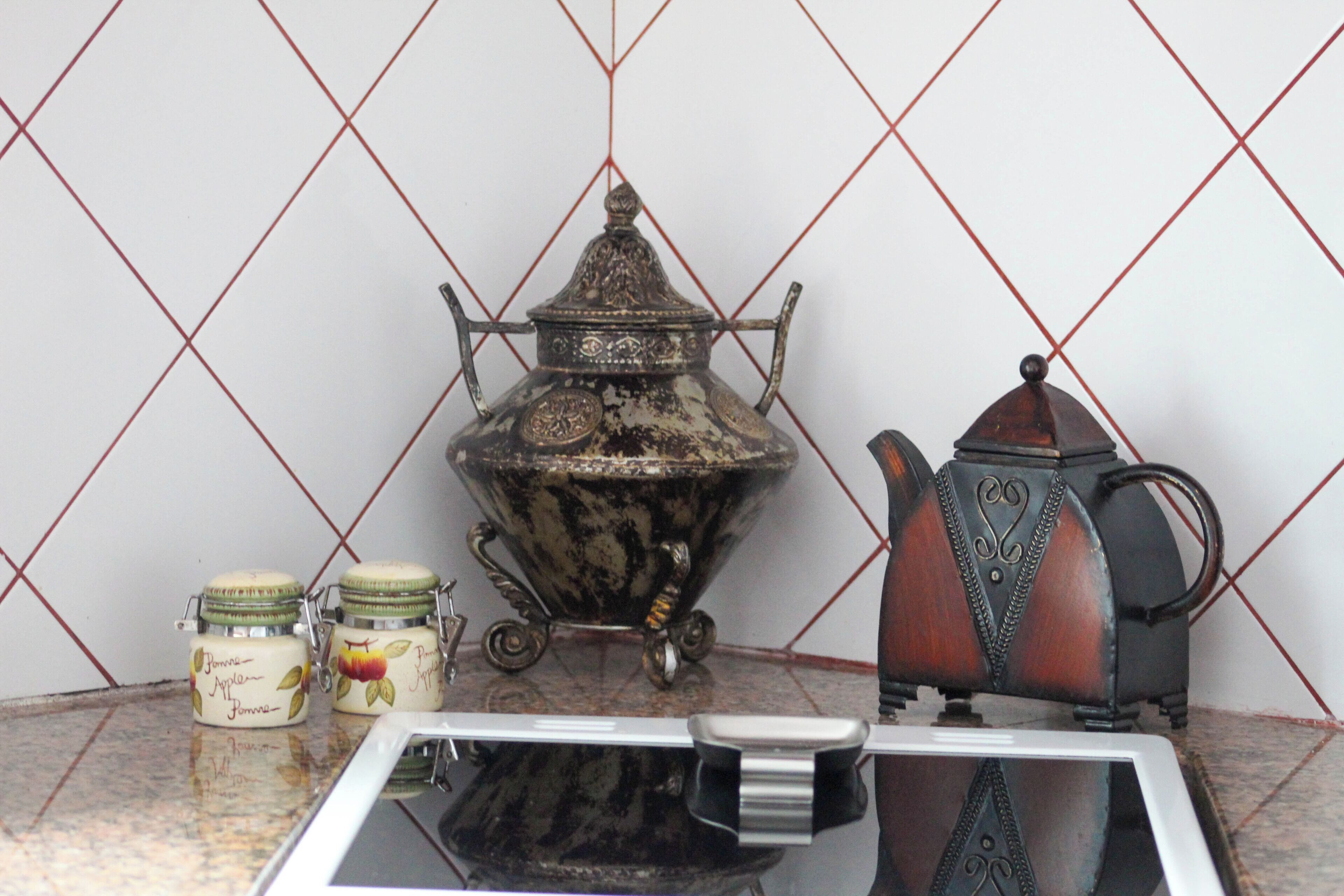 A kitchen counter with a coffee maker, a teapot, and two jars.