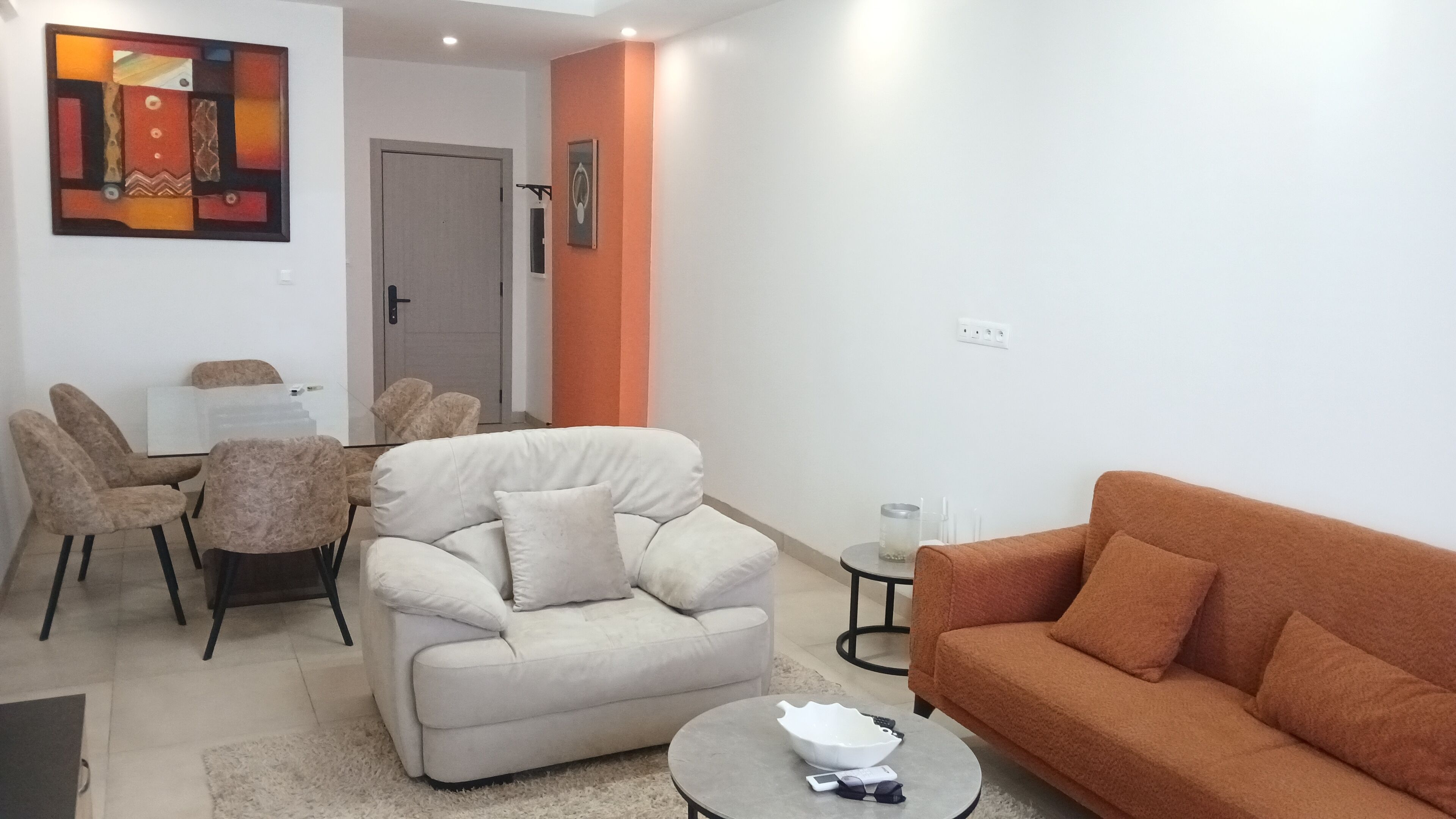 Un salon comprenant un canapé, des fauteuils, une table basse et un coin repas avec des chaises et une table.