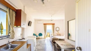 Una habitación de hotel compacta con kitchenette, comedor, cama y baño.
