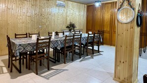A dining area with a long table and chairs, wooden walls, and a ceiling with exposed beams. - Holiday Garden Tbilisi (Tbilisi)