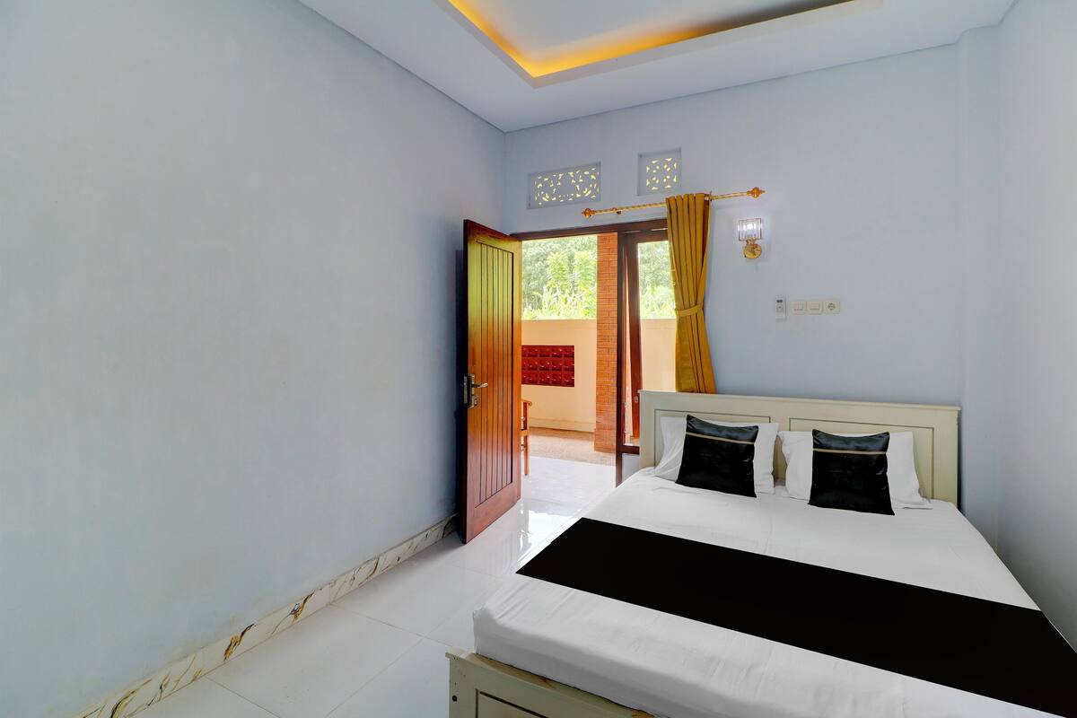 A bedroom with a bed, a door leading to an outdoor area, and a light fixture on the wall.