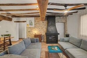 Una sala de estar acogedora con chimenea de piedra, vigas de madera y un conjunto de sofá azul.