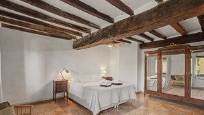 A bedroom with a large bed, a nightstand, a mirror, and a wooden ceiling.