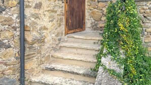 A stone building with a wooden door, a wooden window, and a stone staircase.