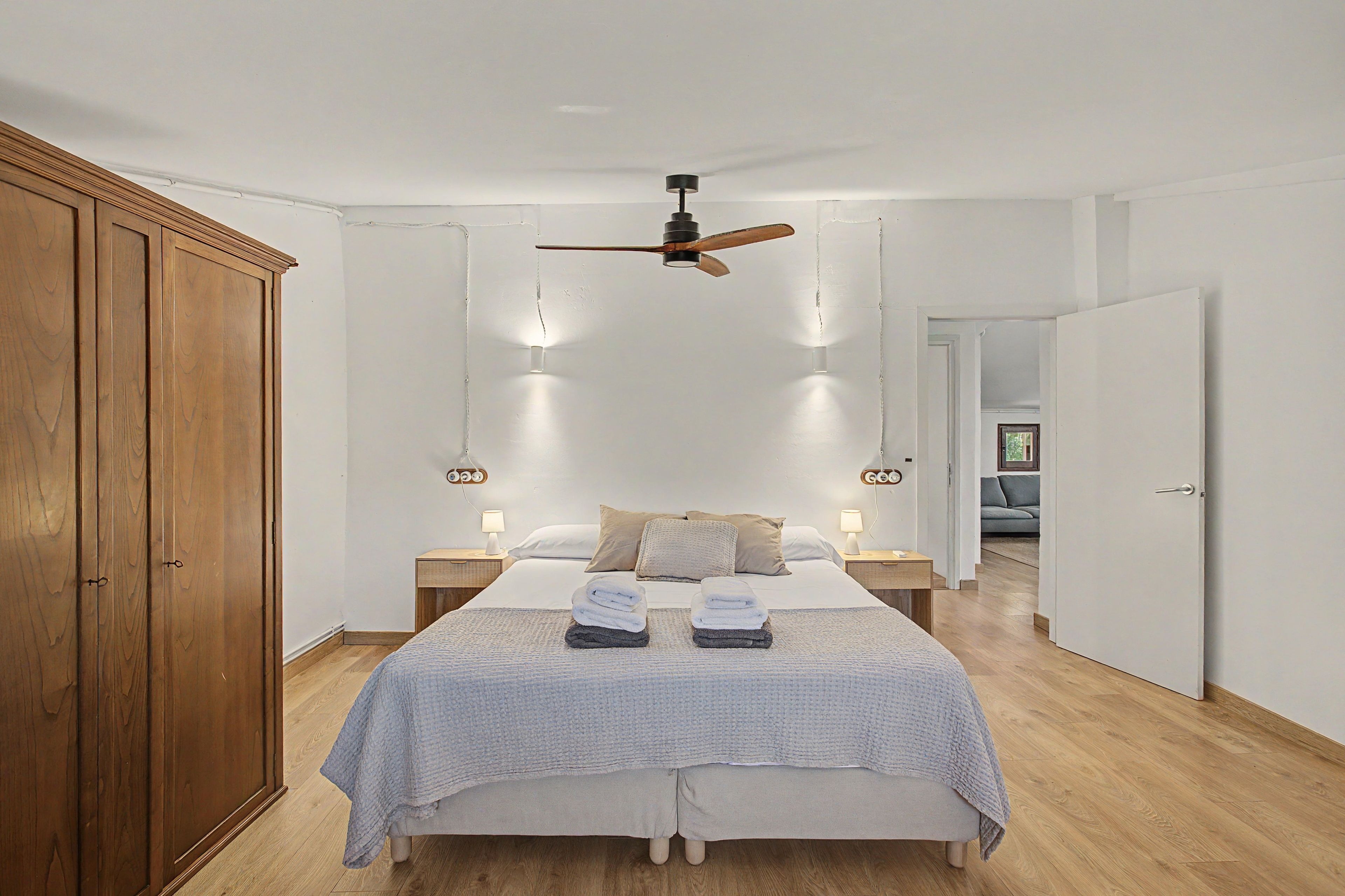 Una camera da letto con un letto, comodini, un armadio e una ventola a soffitto.
