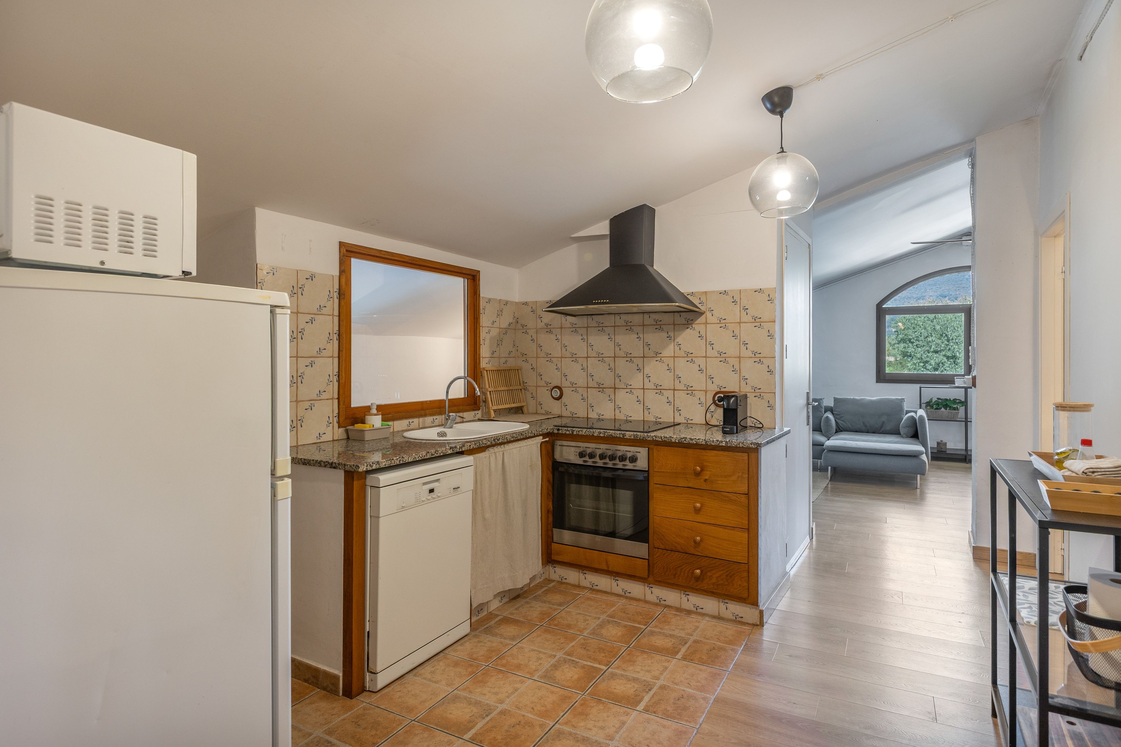 A compact kitchen with a built-in oven, a sink, and a stove. There is a wooden cabinet and a countertop.