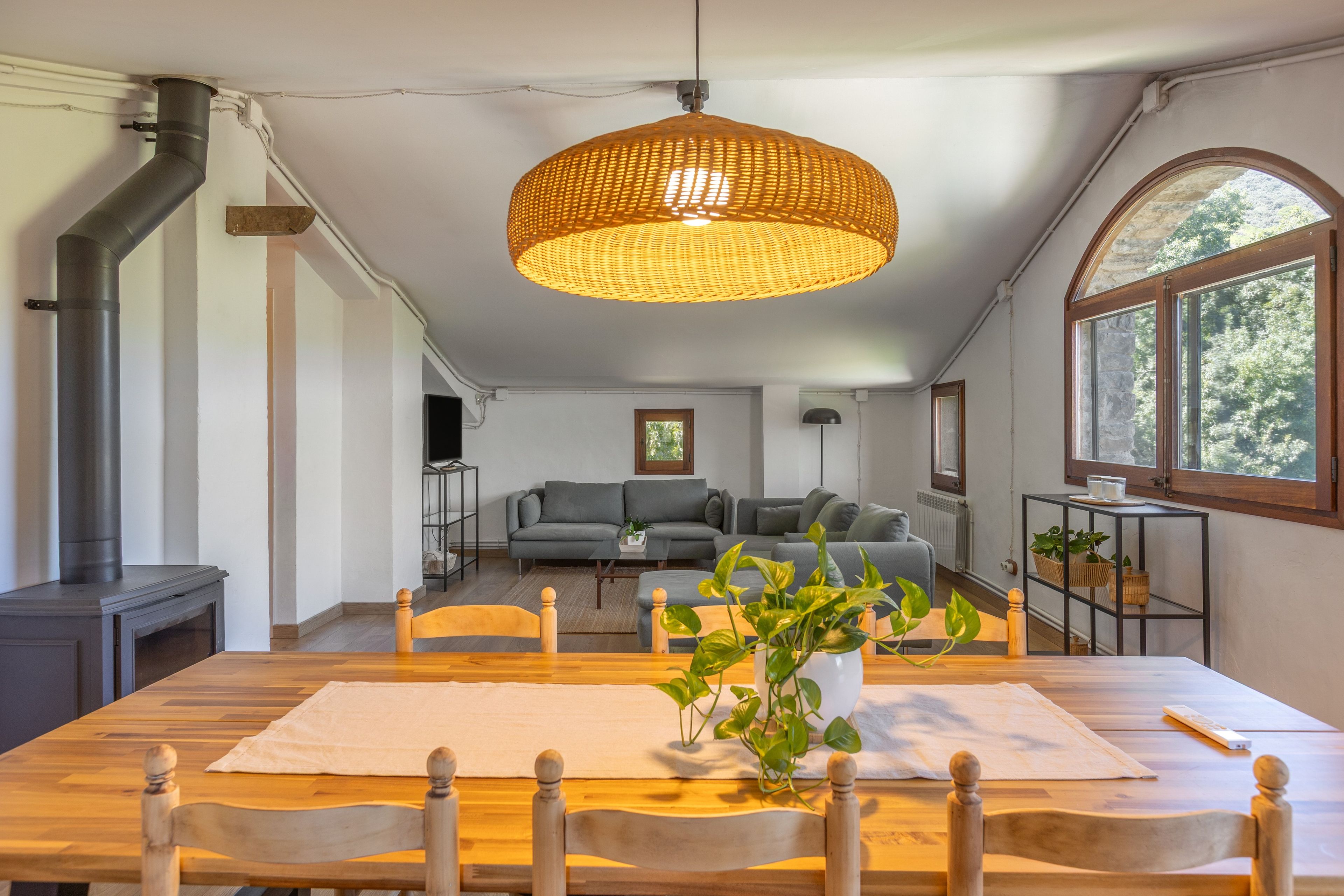 Een moderne woonkamer met een eethoek, een groot raam en een open haard.