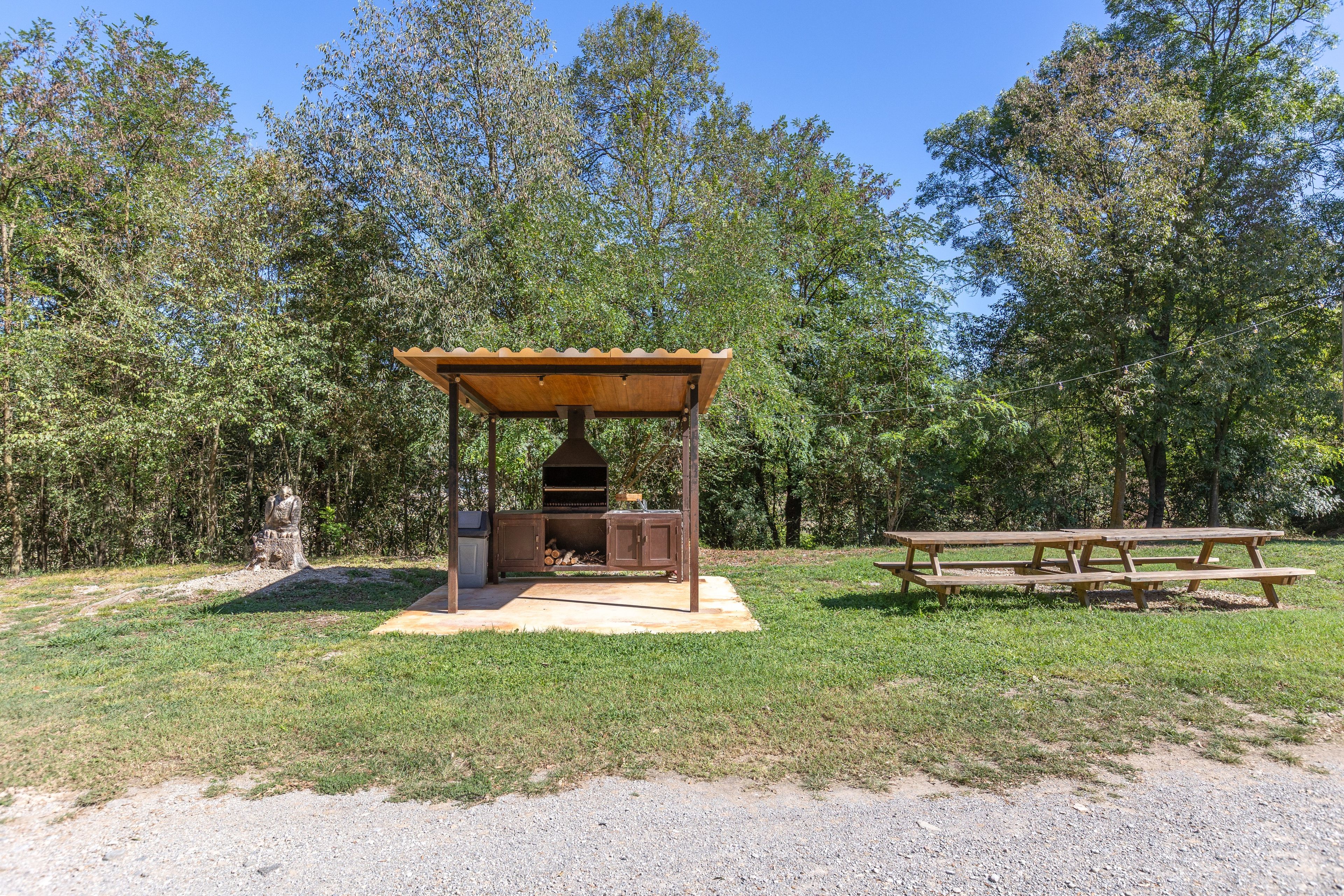 Een buitenbarbecuezone met een grill, een overdekte zithoek en een picknicktafel.
