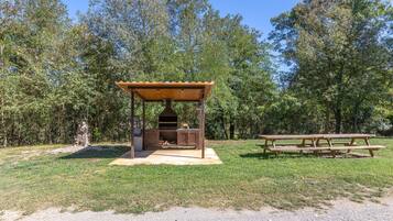 Een buitenbarbecuezone met een grill, een overdekte zithoek en een picknicktafel.