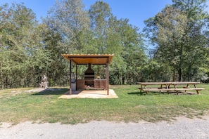 Un área de barbacoa al aire libre con una parrilla, un espacio de estar techado y una mesa de picnic.