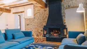 Een gezellige woonkamer met een stenen muur, een open haard en blauwe banken.