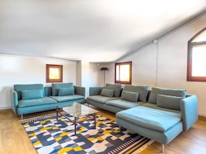 A modern living room with a sectional sofa, a glass coffee table, and a patterned rug.